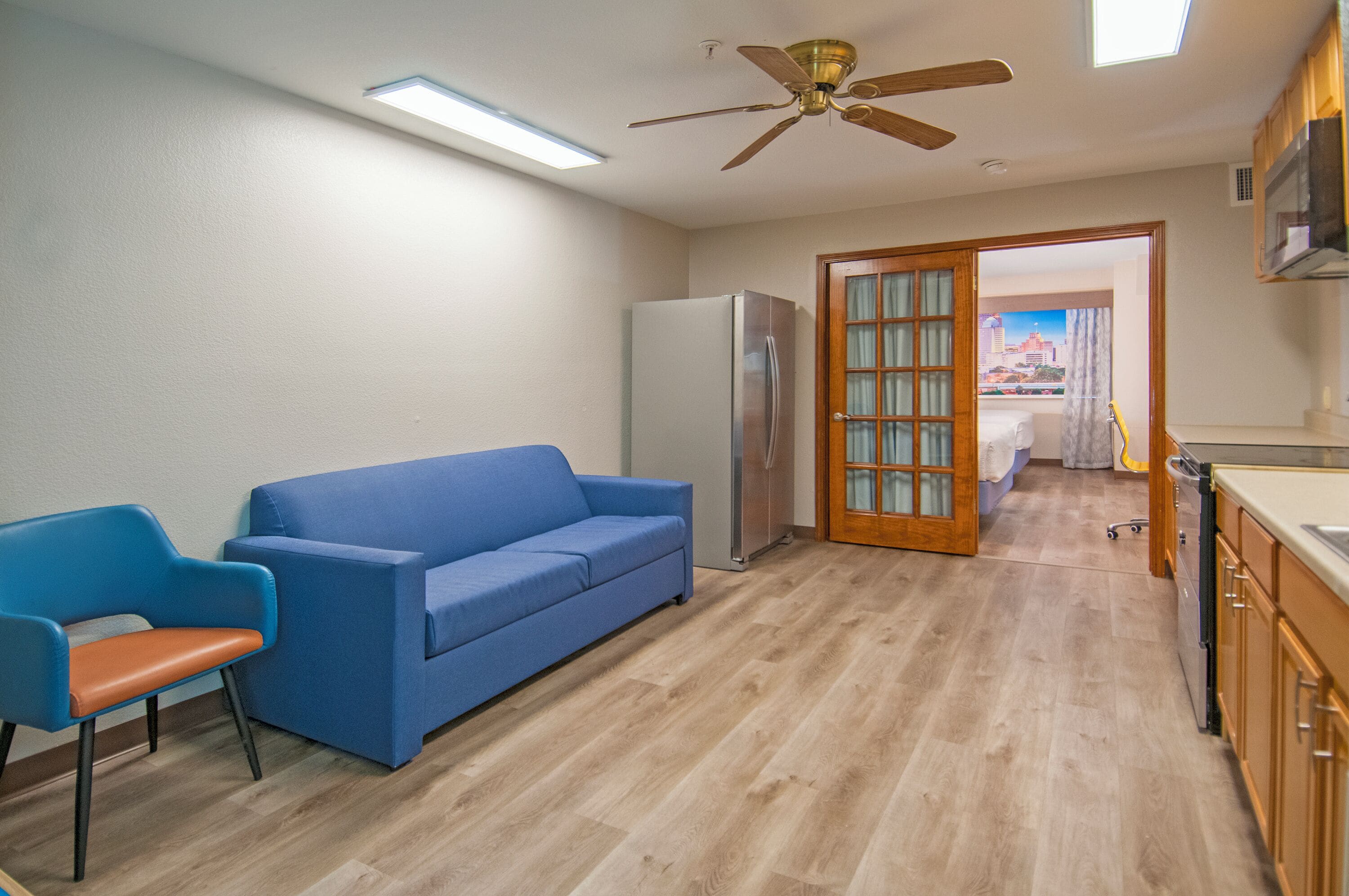 A compact kitchen with a refrigerator, a blue sofa, and a wooden cabinet.