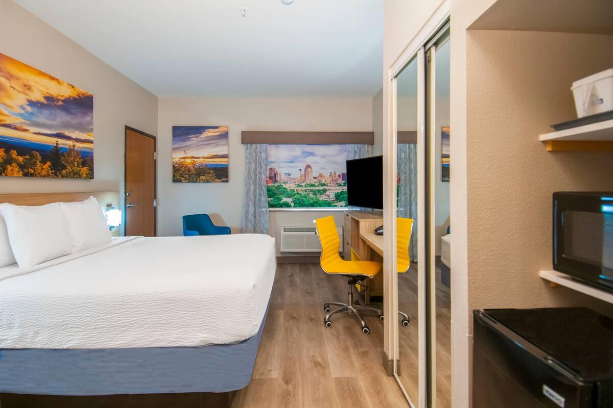 Ein Hotelzimmer mit Bett, Schreibtisch mit Stuhl, Fernseher und Blick auf die Stadt.