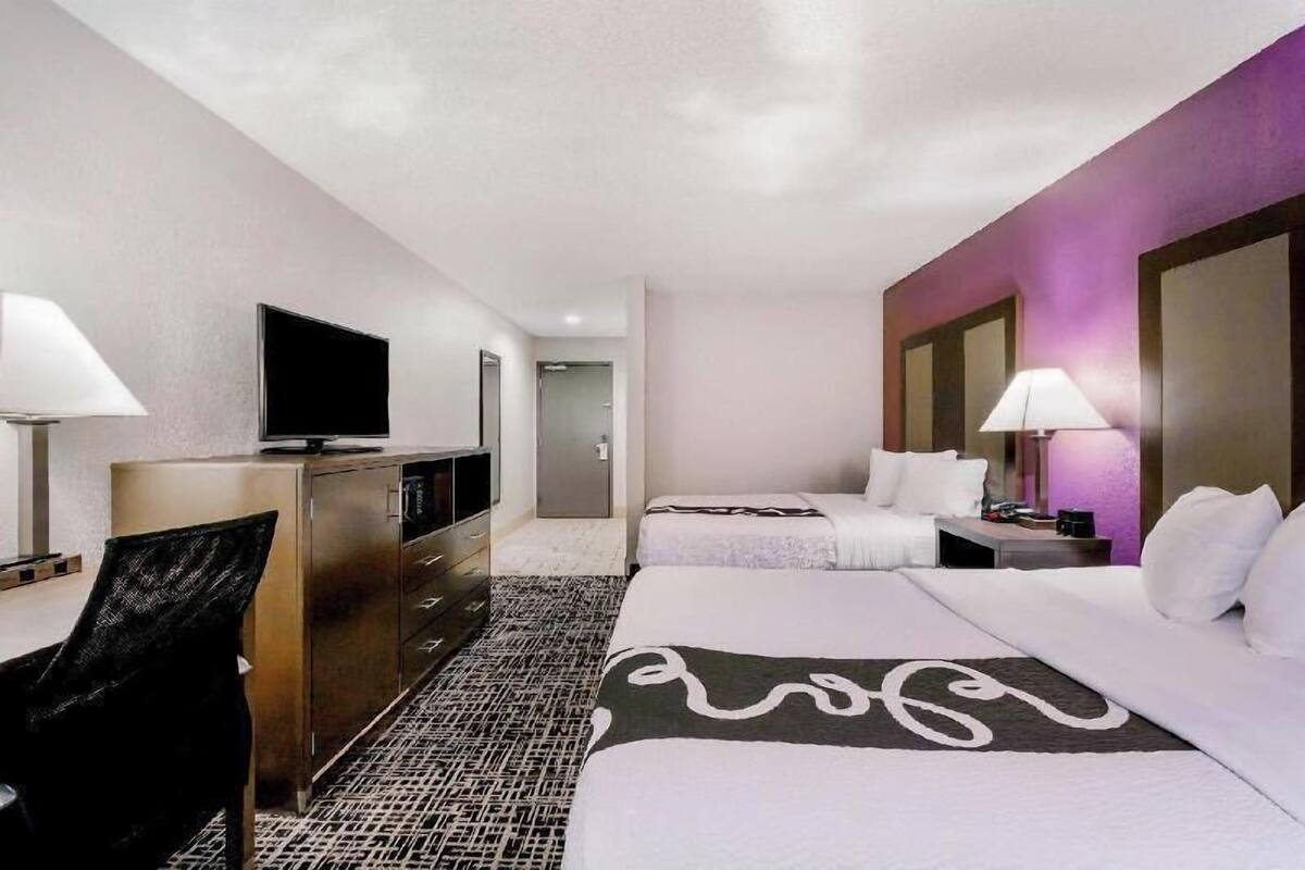 A hotel room with a bed, a desk, a television, and a lamp.