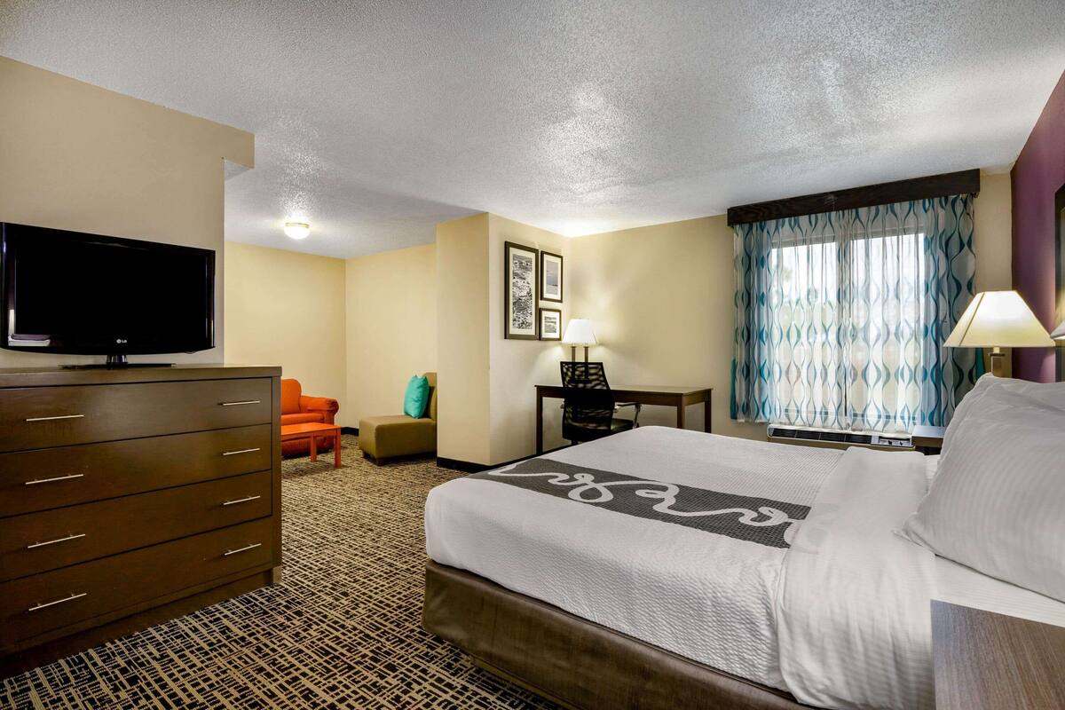 A hotel room with a bed, a dresser, a television, a desk, and a chair.