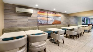 A restaurant with a long counter, cushioned seating, and a large wall mural. - La Quinta Inn by Wyndham North Myrtle Beach (North Myrtle Beach)