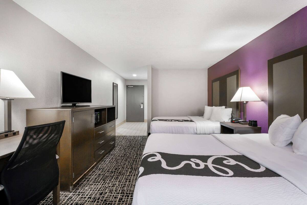 A hotel room with a bed, a desk, a TV, and a bathroom.