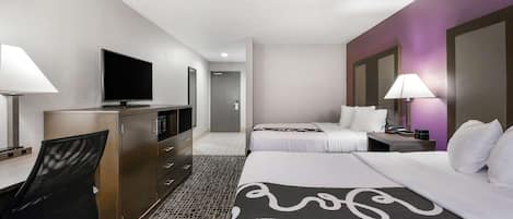 A hotel room with a bed, a desk, a TV, and a bathroom.