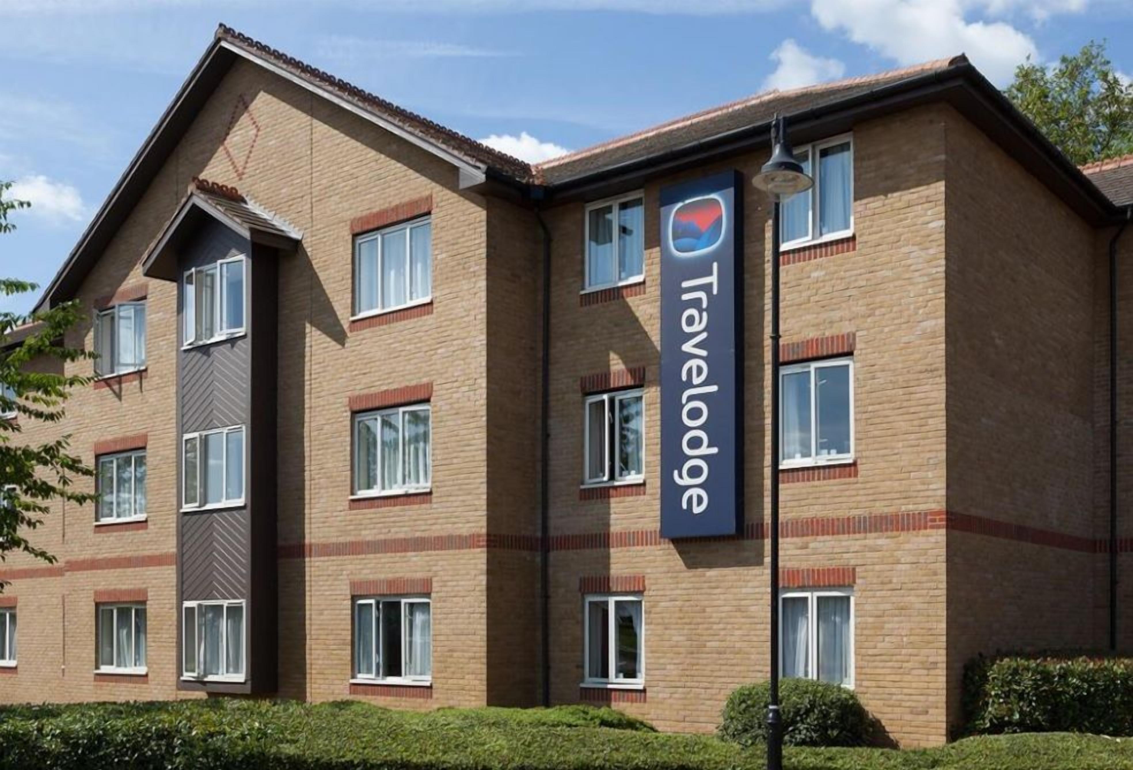 A Travelodge hotel with a brick facade, multiple windows, and a prominent Travelodge sign.