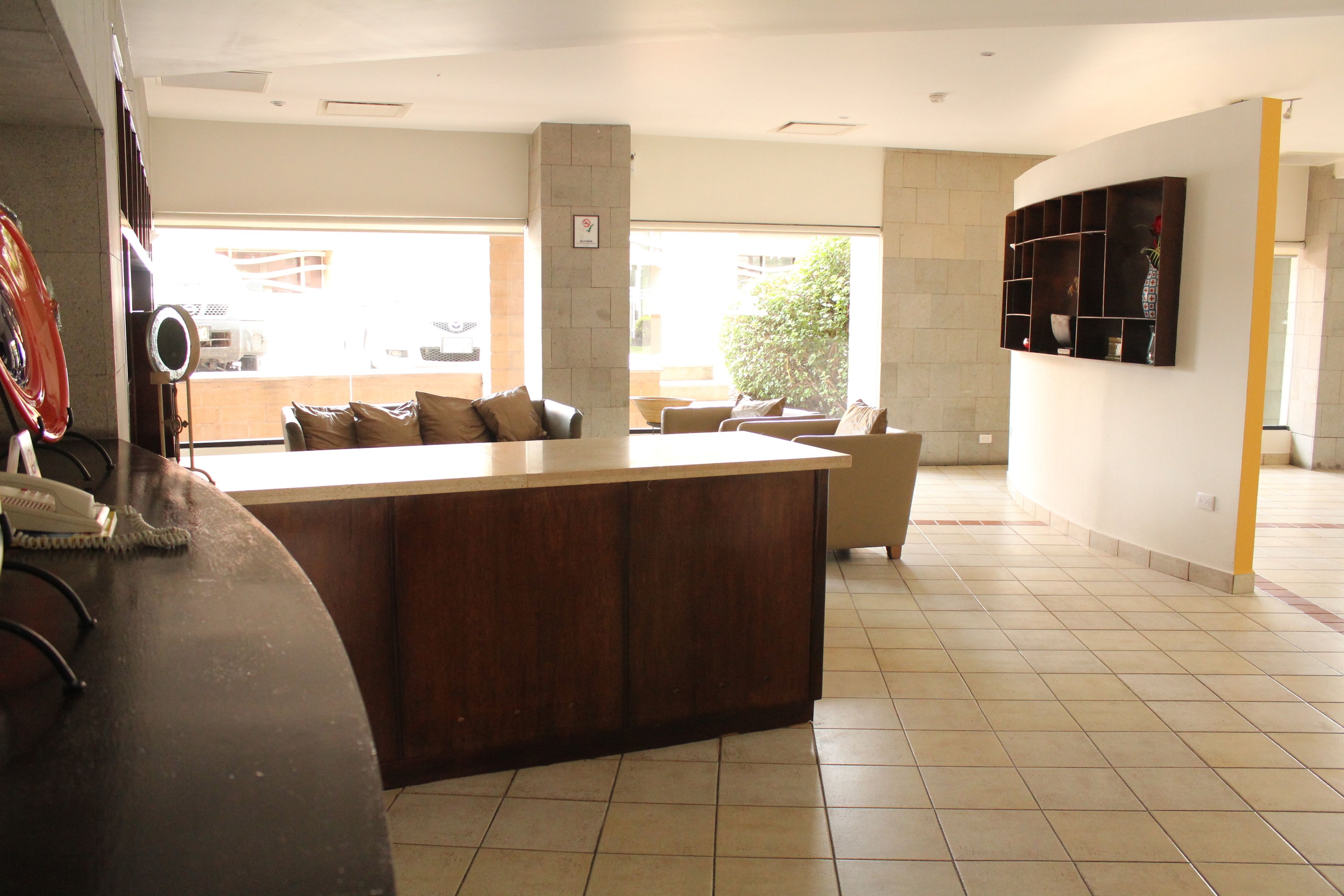 A modern kitchen with a central island, a dining area with a sofa, and a large window providing natural light.