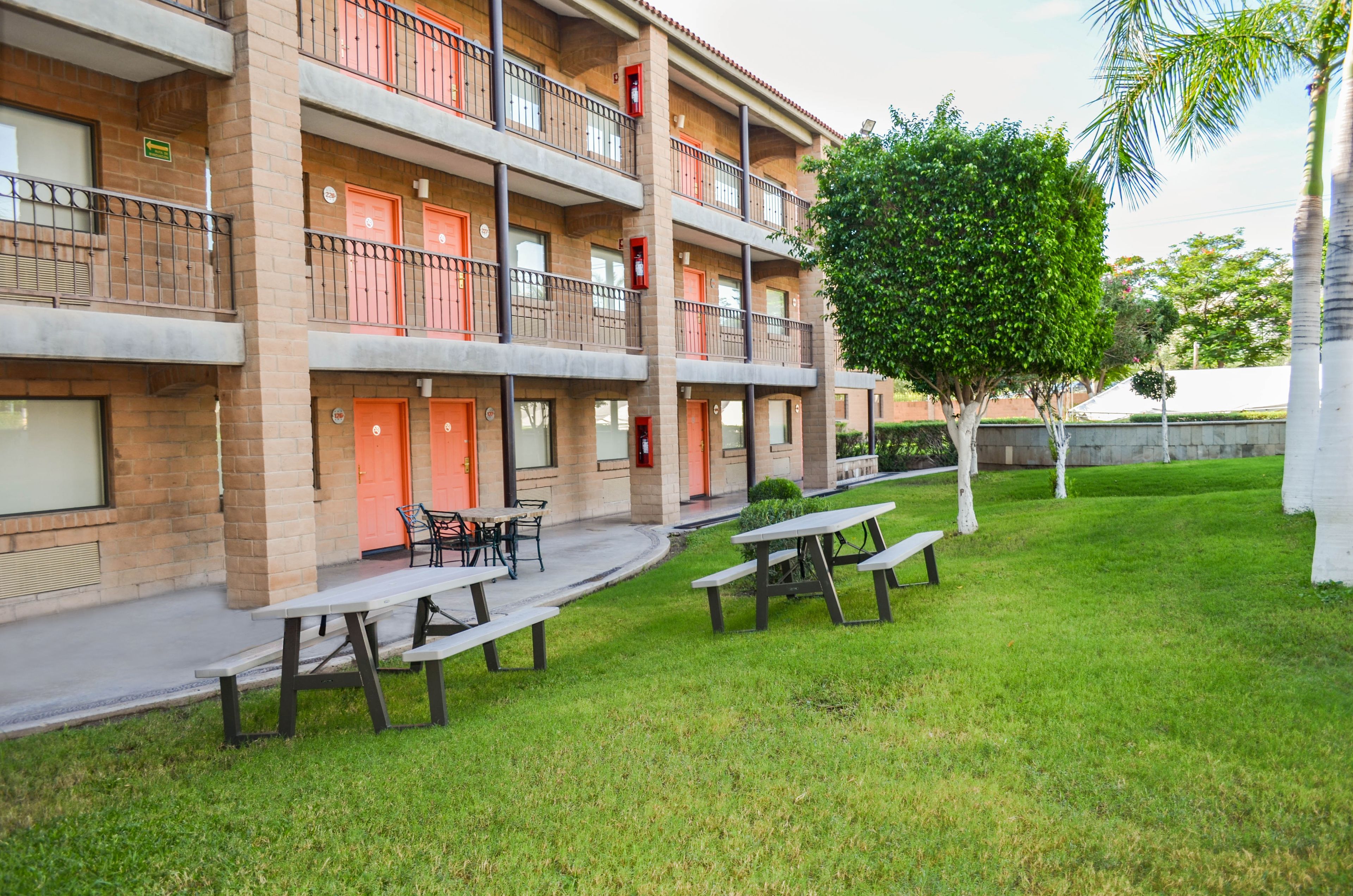 A multi-story building with balconies, outdoor seating, and a well-maintained lawn.