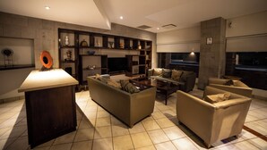 A modern living room with a sofa set, a coffee table, and a TV. There is a fireplace and a stone wall.