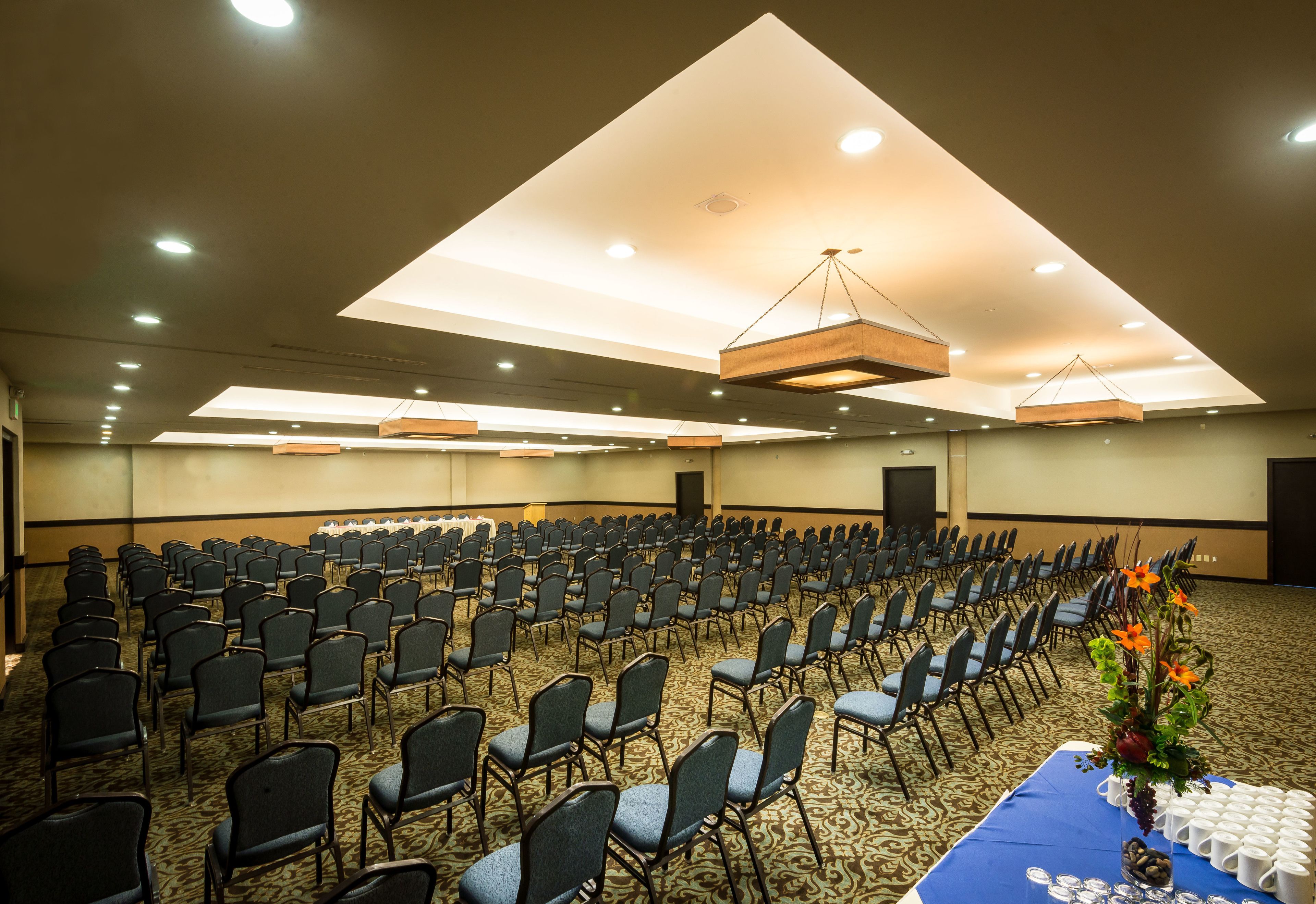 A conference room with rows of chairs, a table with a blue tablecloth, and a floral centerpiece.