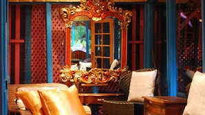 A room with a wooden ceiling, a large ornate mirror, wicker furniture, and a tiled floor. - Half Moon Blue (Scarborough)