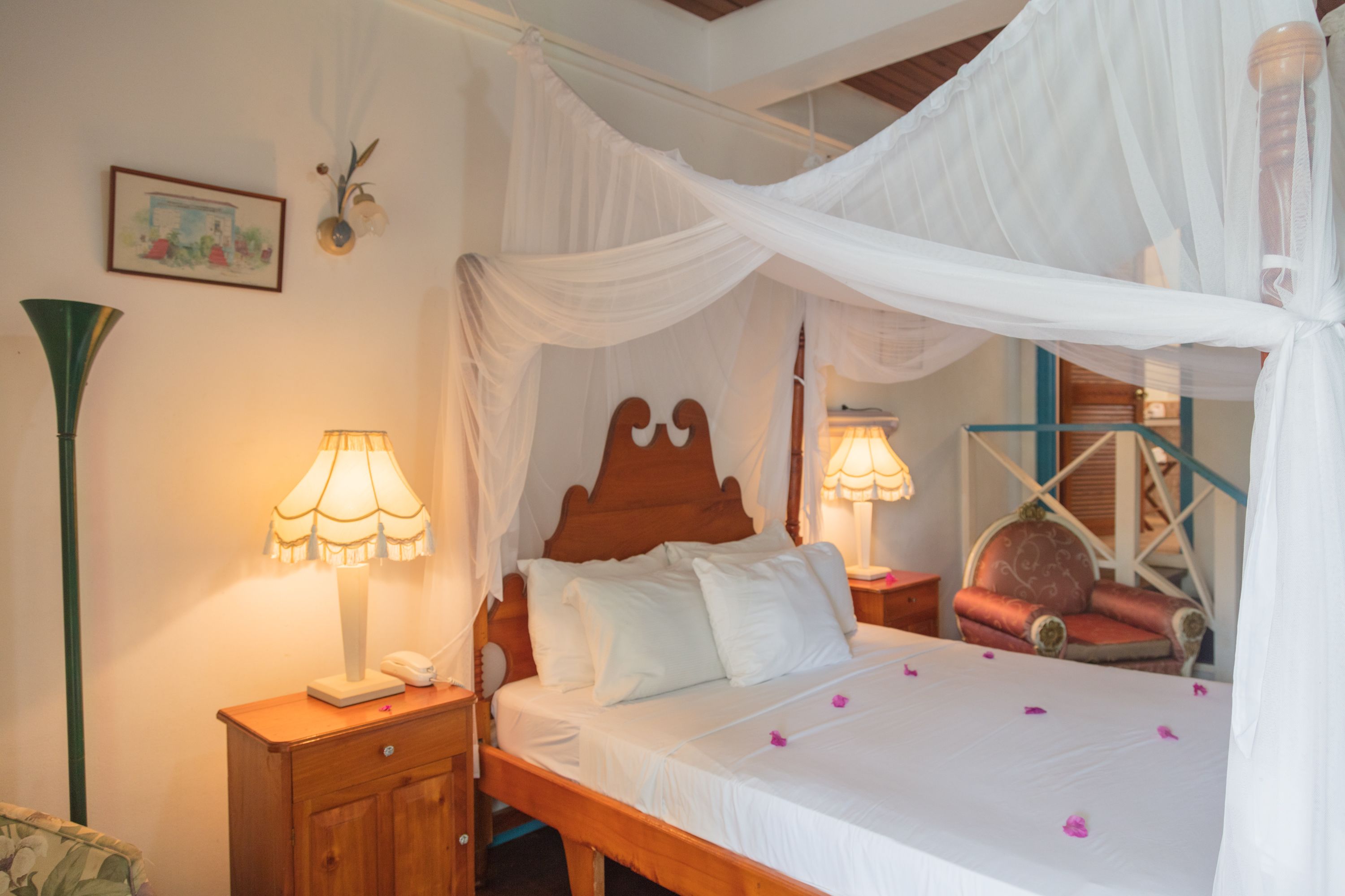 Une chambre à coucher avec un lit à baldaquin, des lampes de chevet, une table de chevet en bois et une chaise avec un coussin.