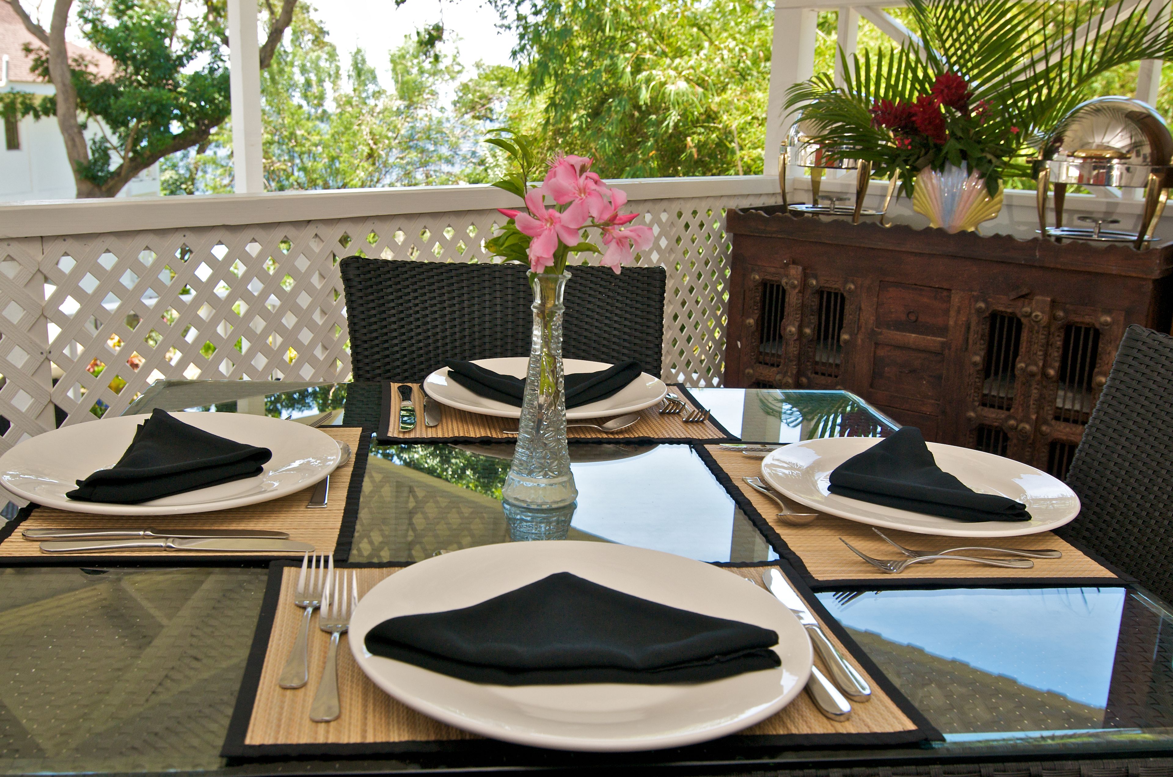 A dining table set with plates, cutlery, and a vase with flowers.