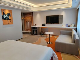 Una habitación de hotel moderna con cama, zona de estar, escritorio y televisor.