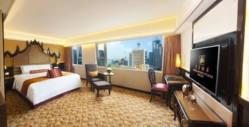 Habitación de hotel con cama, escritorio, silla, televisor y vistas a la ciudad.