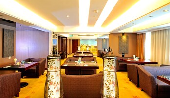 Un hall de hotel con zonas de estar, un mostrador de recepción y vistas al área del bar.