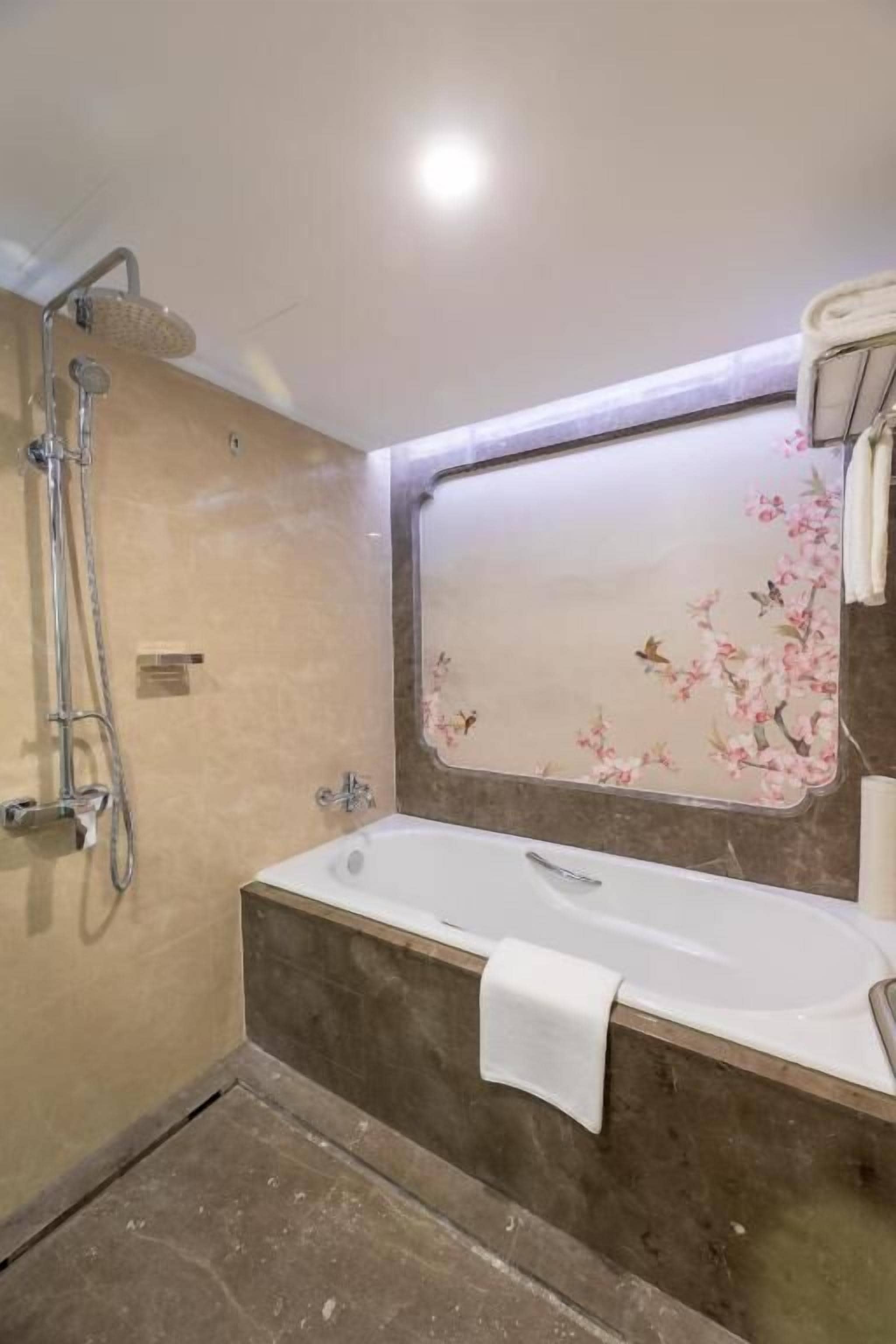 A bathroom with a bathtub, a shower, and a mirror with floral wallpaper.