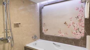 A bathroom with a bathtub, a shower, and a mirror with floral wallpaper.
