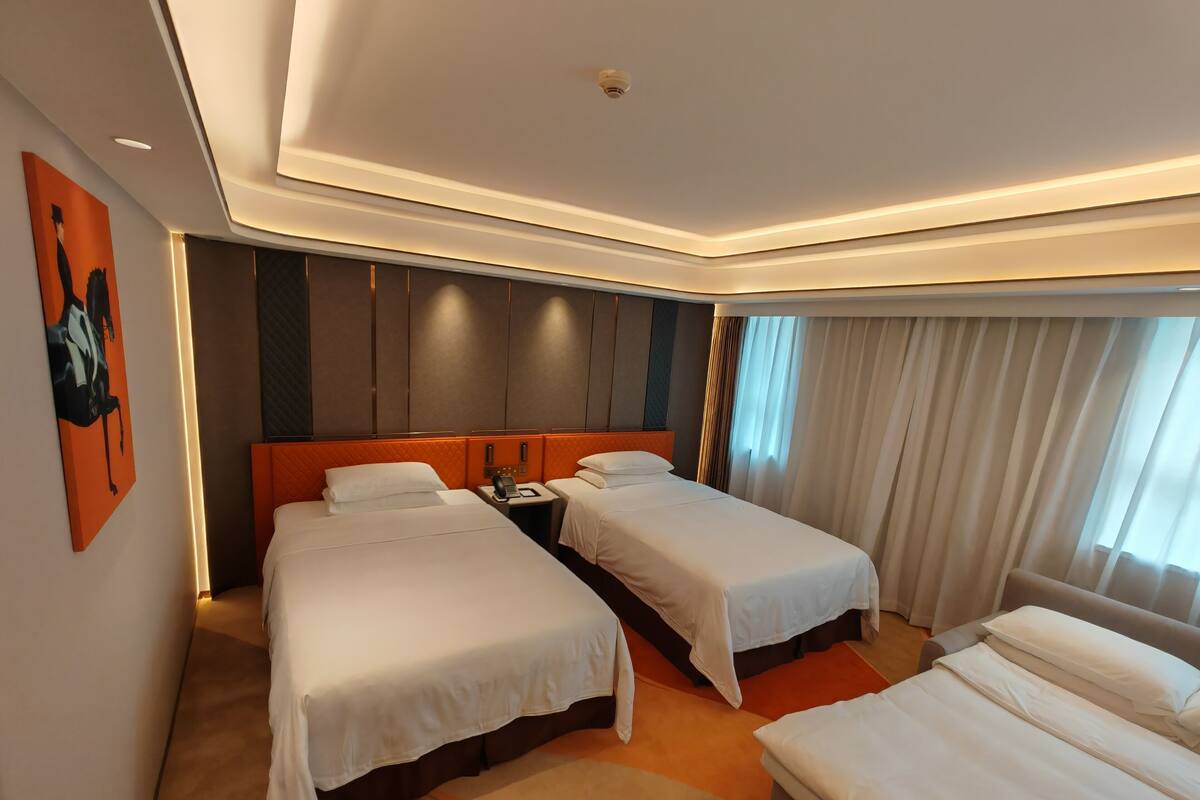 Habitación de hotel con dos camas, un ventanal grande con cortinas y un diseño moderno con alfombra color beige.