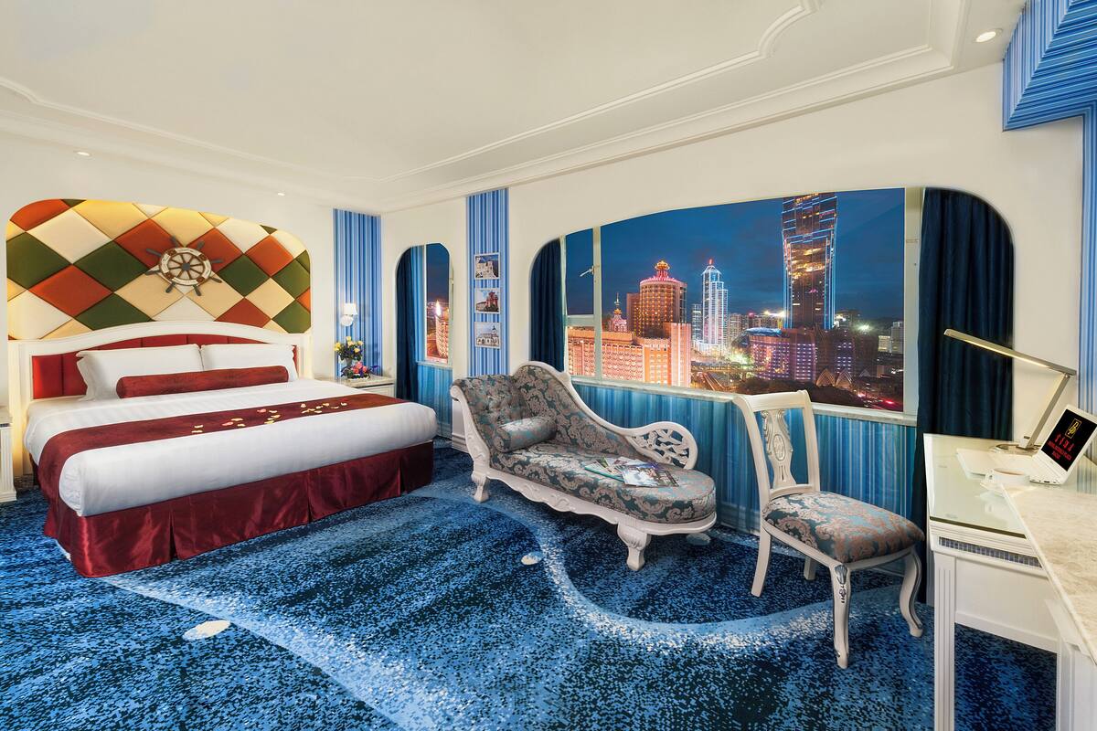 Habitación de hotel con una cama grande, un sofá, un escritorio y vistas a la ciudad.