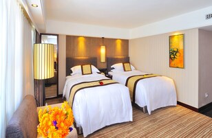 A hotel room with two beds, a sofa, a lamp, and a painting on the wall.