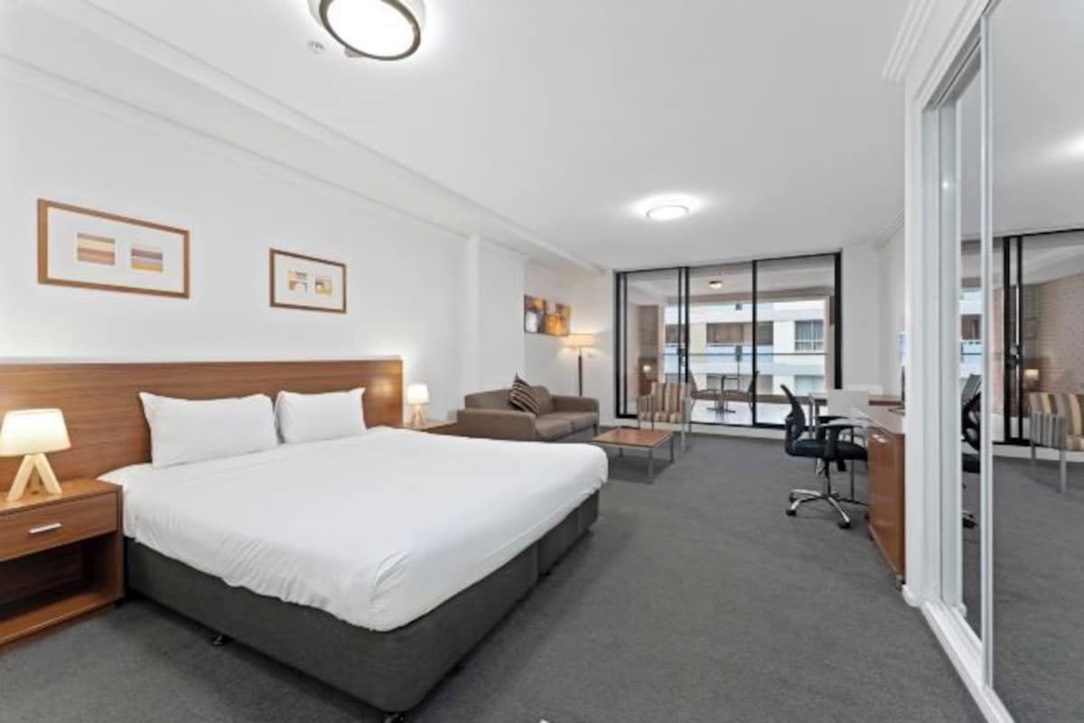 Una habitación de hotel moderna con una cama grande, un escritorio y un sofá.