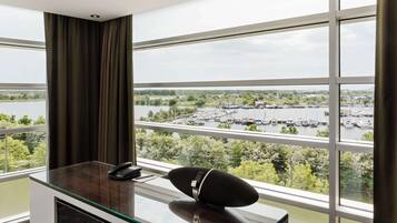 Habitación de hotel con un ventanal grande que ofrece vistas a un puerto deportivo y al agua.