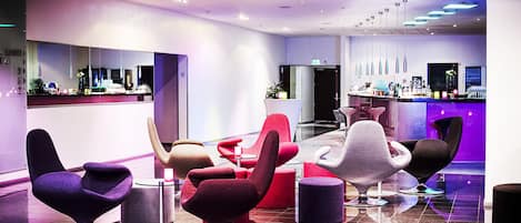 Un vestíbulo moderno con asientos contemporáneos, una zona de recepción y un bar.