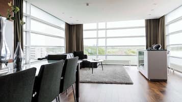 A modern living room with a sofa, chairs, a coffee table, and a large window with curtains.