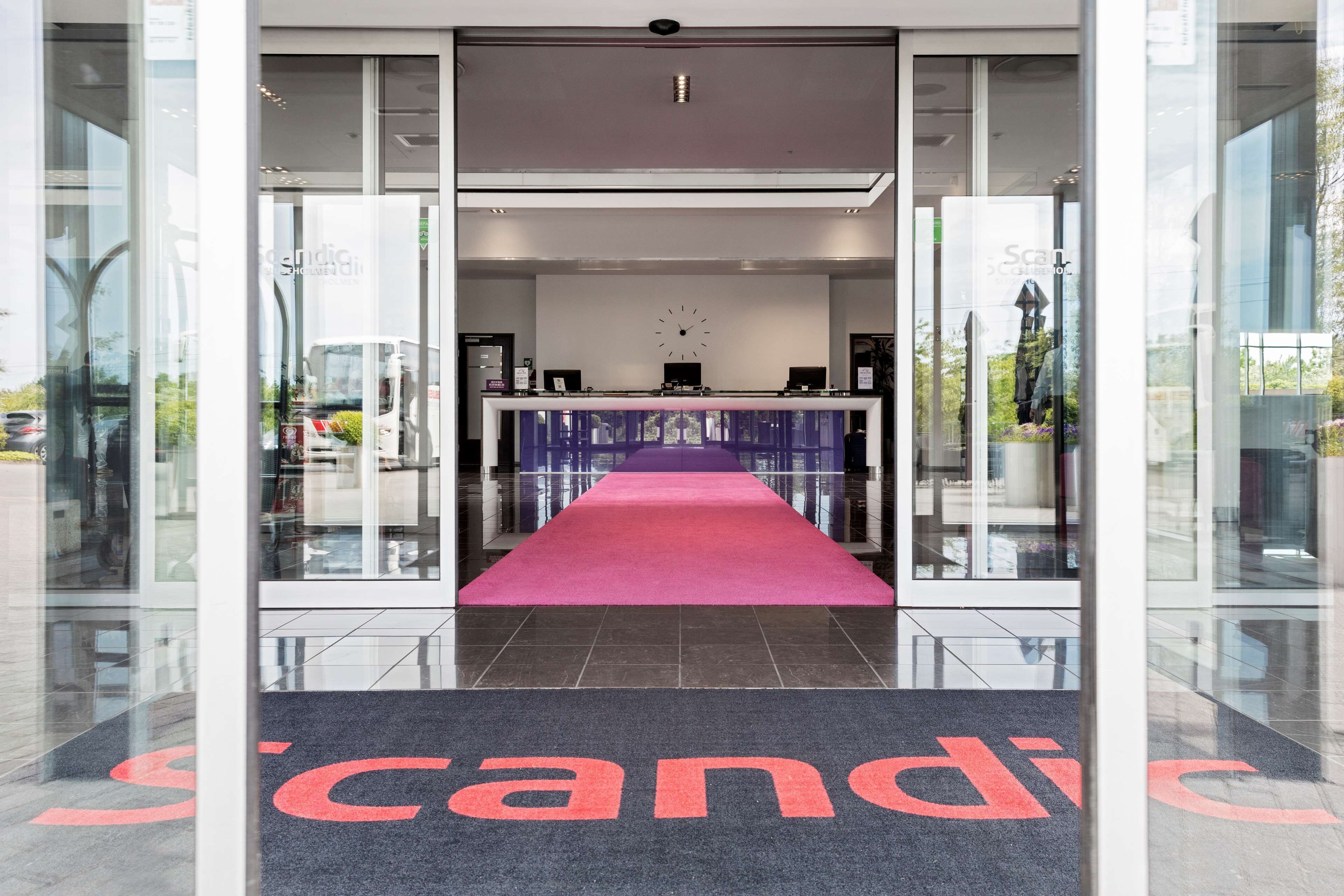 Entrada de un hotel con alfombra roja que conduce a la recepción.