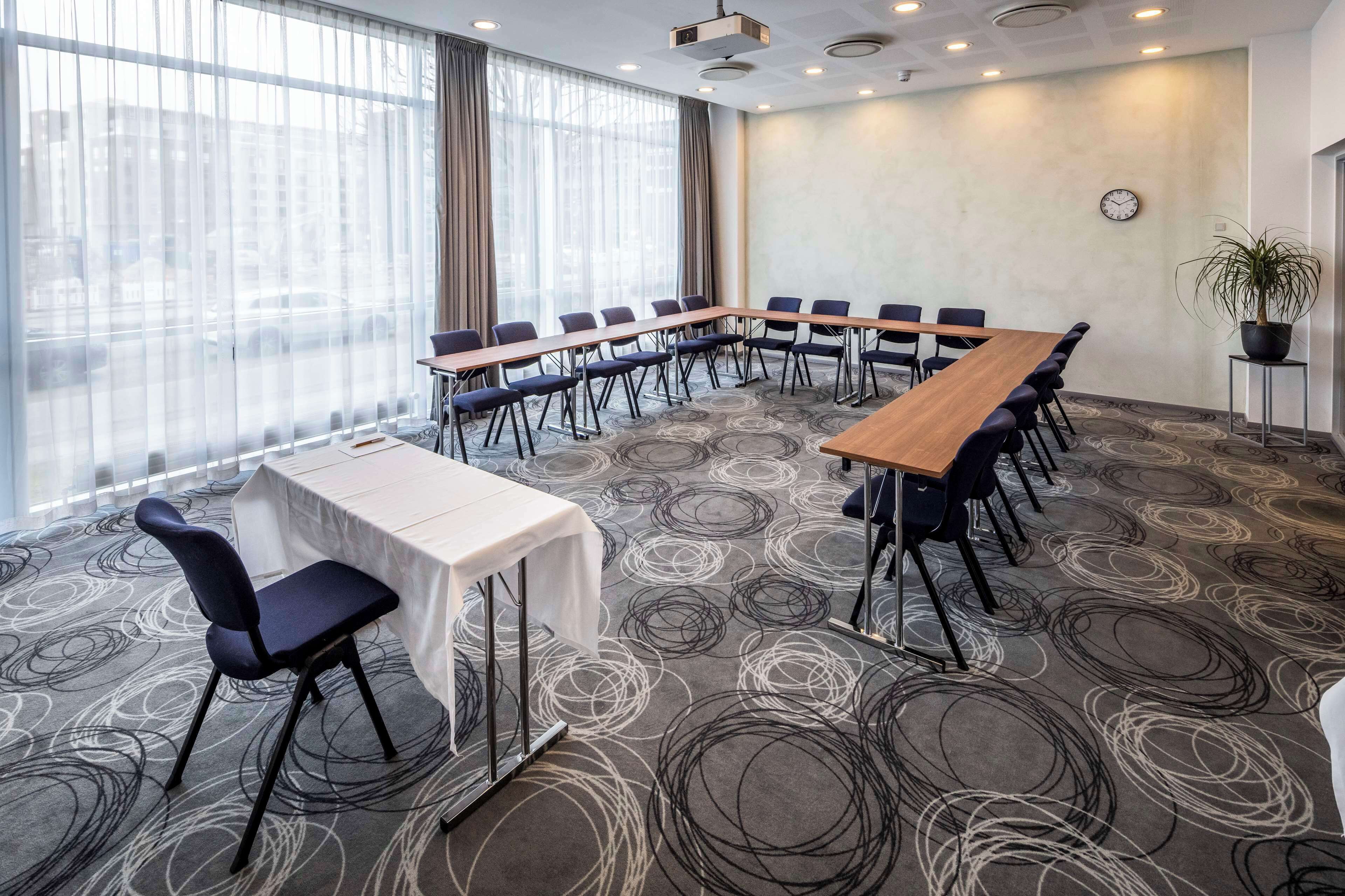A conference room with a long table, chairs, and a clock on the wall.