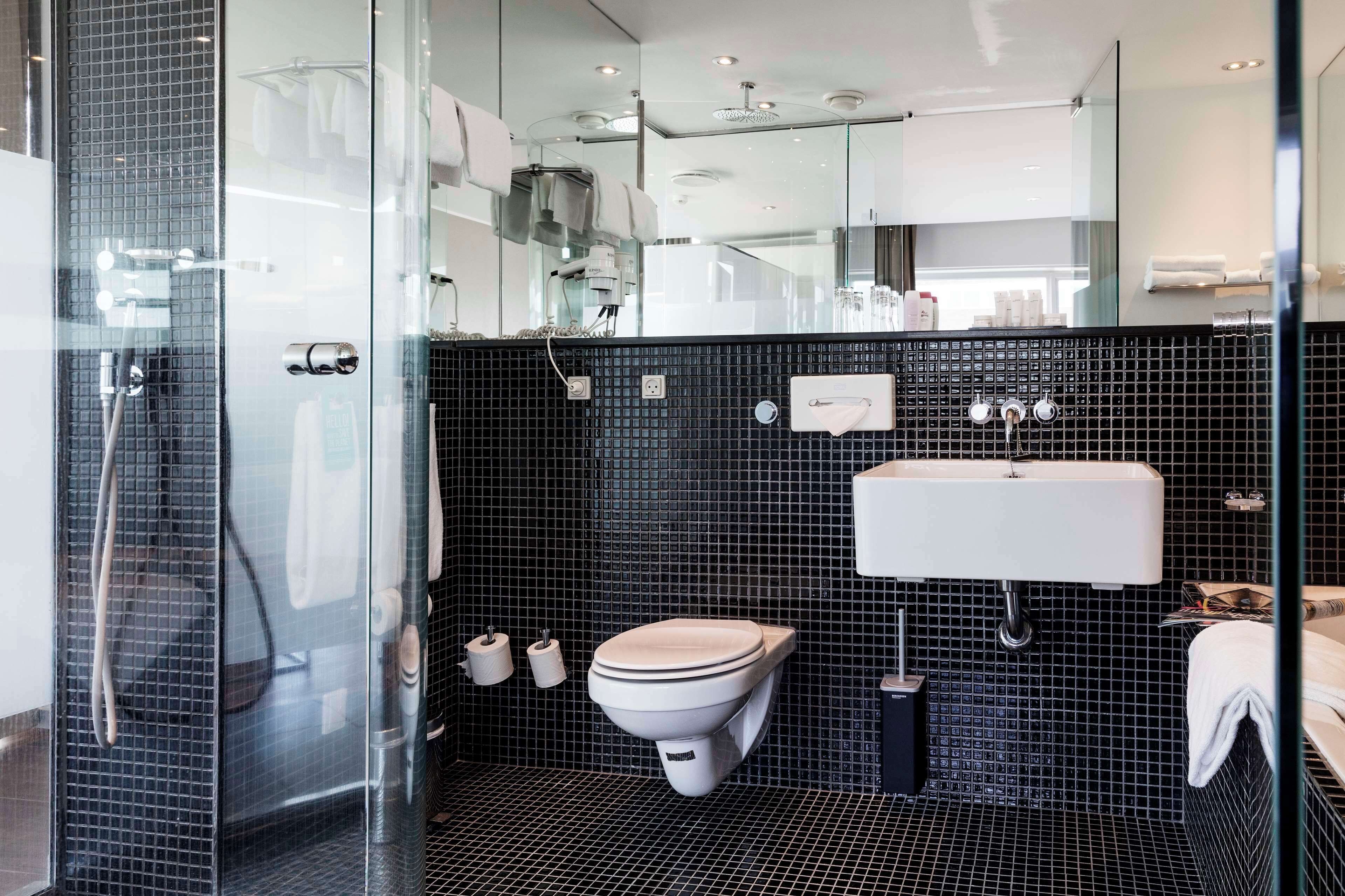 Un baño moderno con cabina de ducha de vidrio, inodoro, lavamanos y espejo.