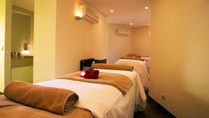 A hotel room with two beds, each with a towel and a red candle. There are wall-mounted air conditioners and a mirror on the left wall. - The Views Monumental (Funchal)