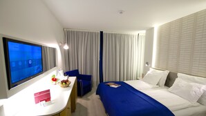 A hotel room with a bed, a desk, a chair, and a television. - The Views Monumental (Funchal)