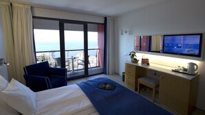 A hotel room with a bed, a desk, a chair, a TV, and a view of the sea. - The Views Monumental (Funchal)