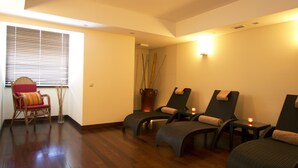 A room with wooden flooring, a wicker chair with a cushion, and three reclining chairs with towels. - The Views Monumental (Funchal)
