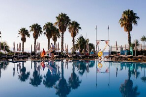 Una piscina al aire libre, sombrillas, tumbonas