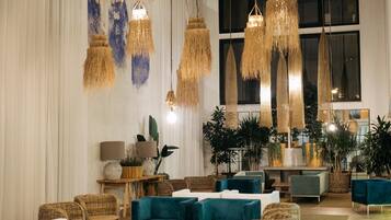 A modern interior with hanging lamps, sofas, and potted plants.