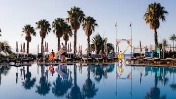 Una piscina al aire libre, sombrillas, tumbonas
