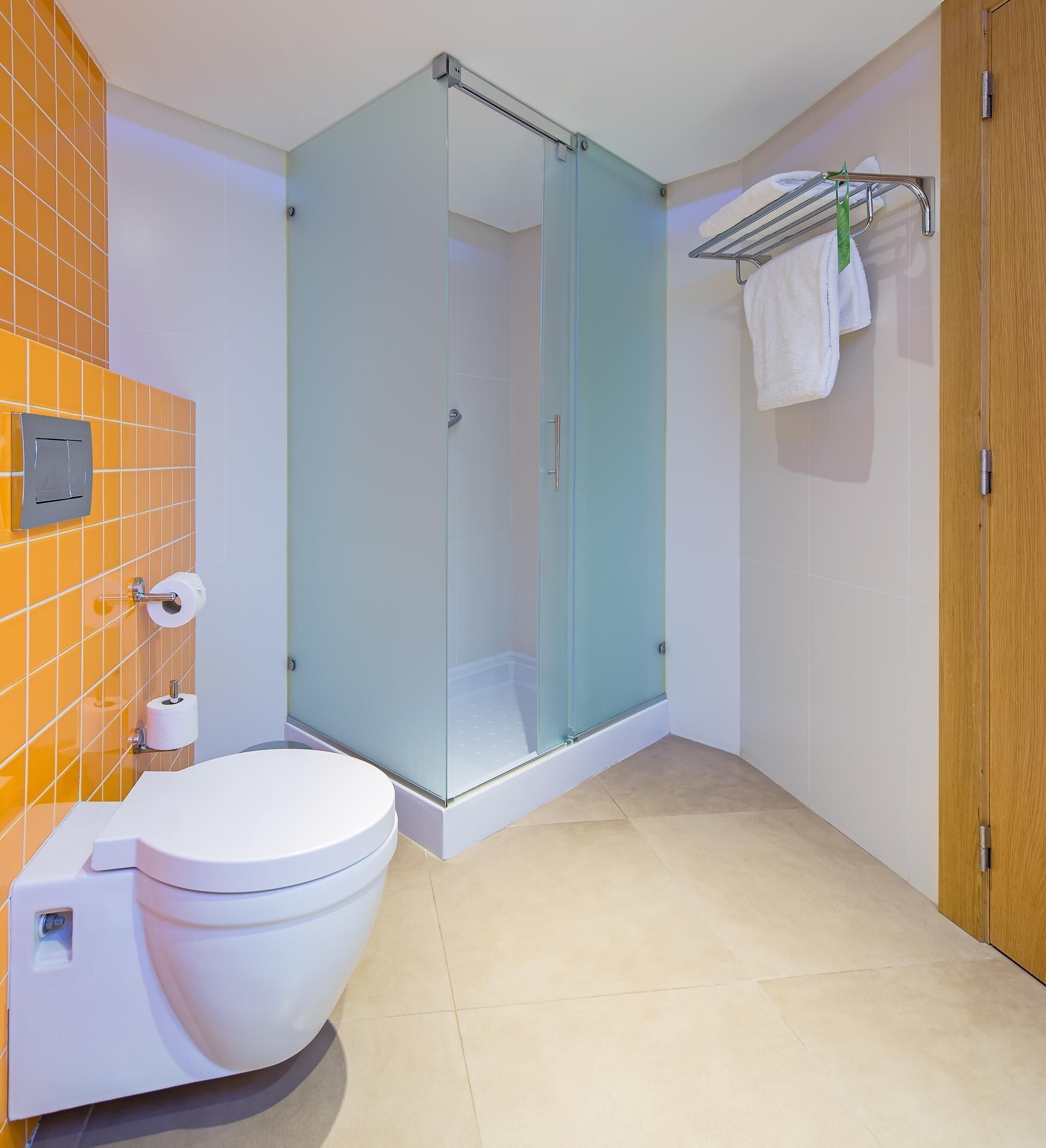A modern bathroom with a glass-enclosed shower, a white toilet, and a towel rack with a hanging towel.