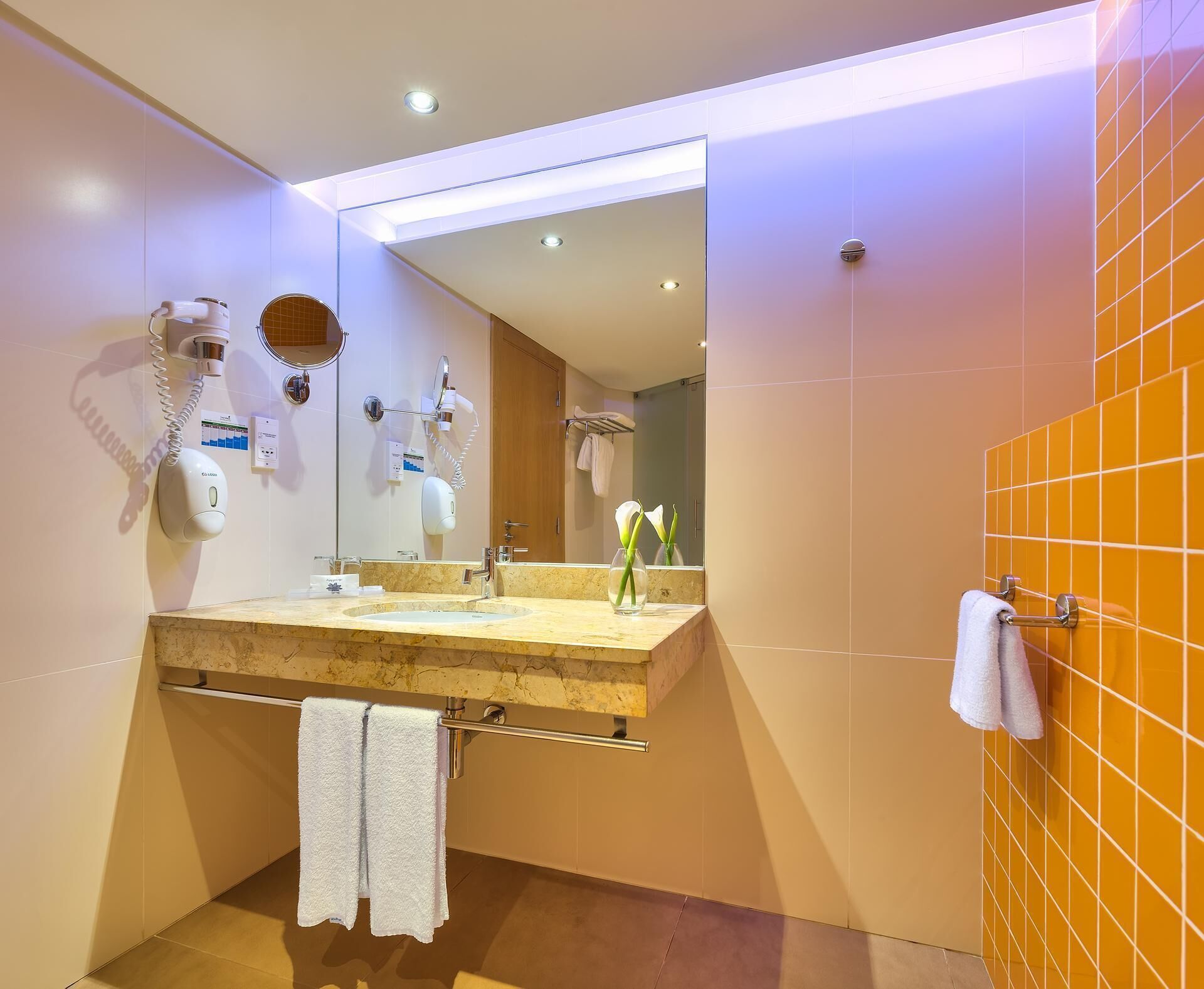 Un baño moderno con un espejo grande, un lavabo con toallero y cabina de ducha.