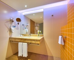 Un baño moderno con un espejo grande, un lavabo con toallero y cabina de ducha.