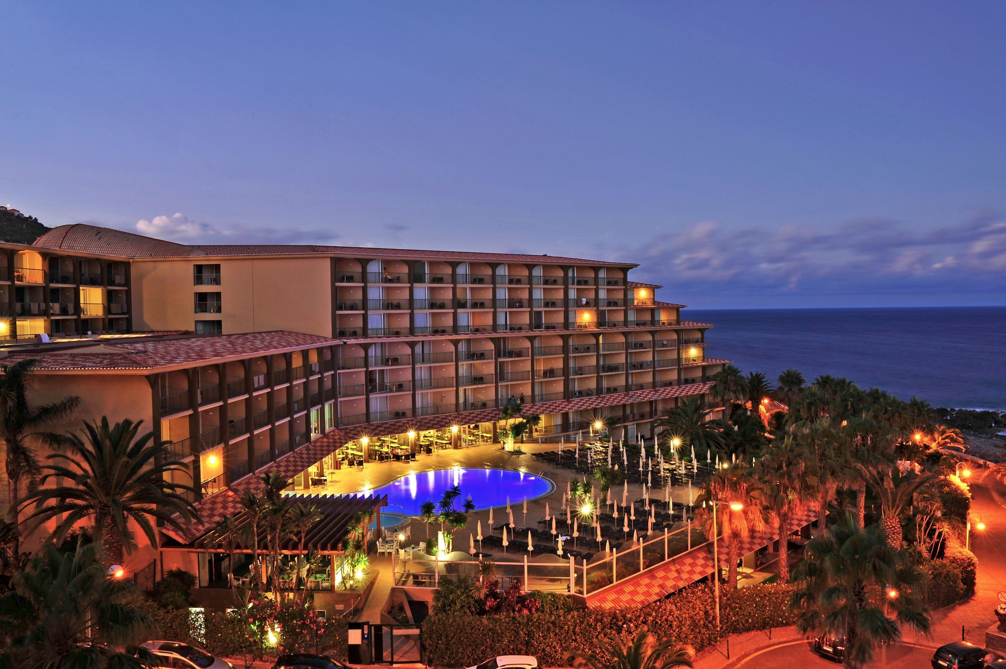 Un hotel con piscina, varios balcones y vistas al mar.