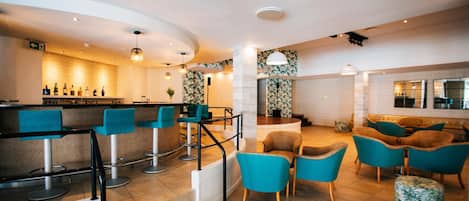 A modern bar area with bar stools, a counter with bottles, and a seating area with sofas and chairs.