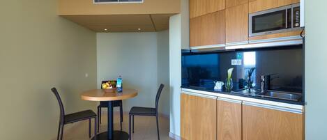 A compact kitchen with wooden cabinets, a microwave, and a small dining table with chairs.