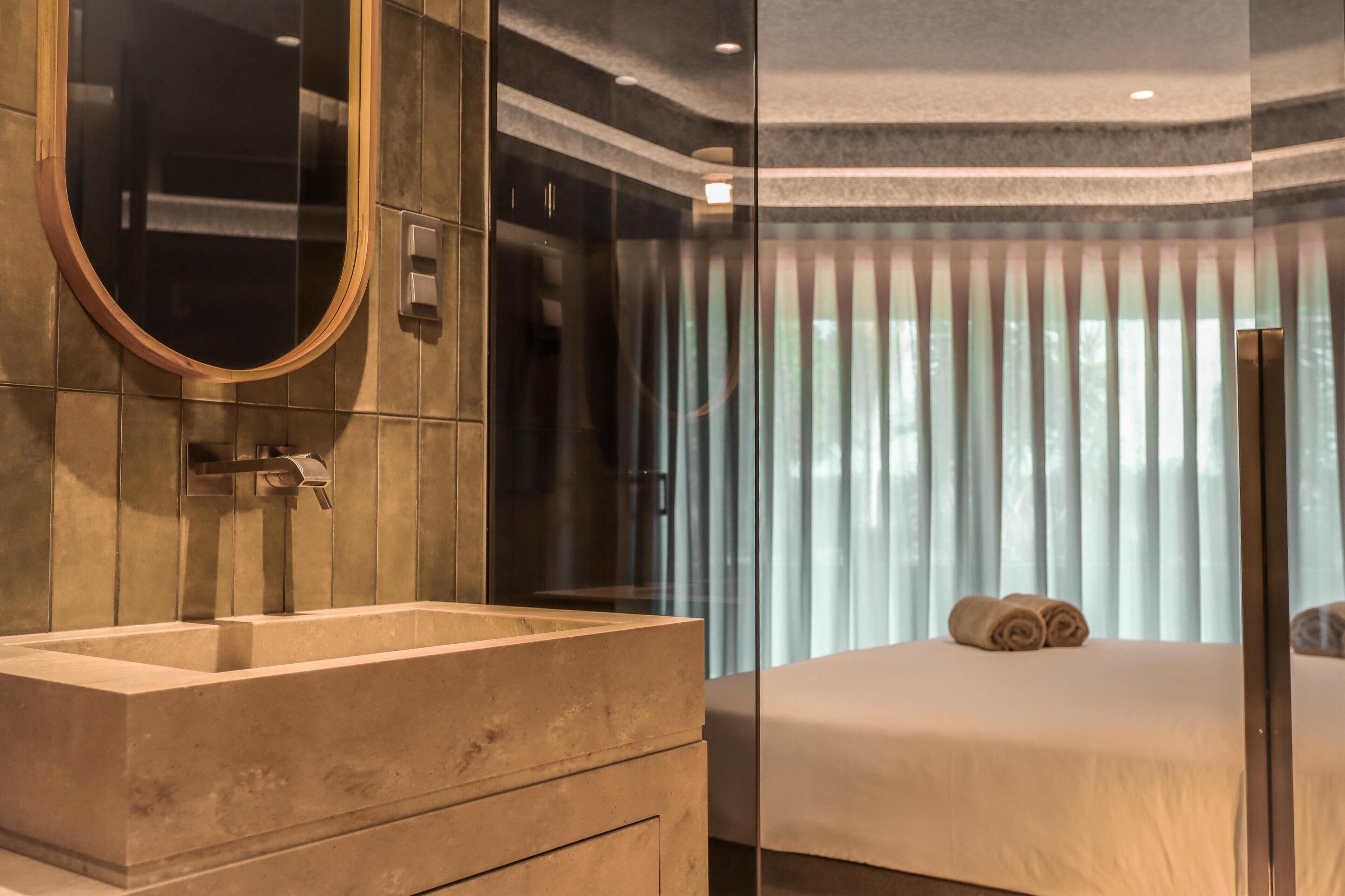Une salle de bain moderne avec un grand miroir, un lavabo rectangulaire et un espace douche.