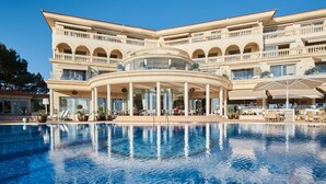 Et stort hotel med en central pool, flere balkoner og udendørs siddeområder.