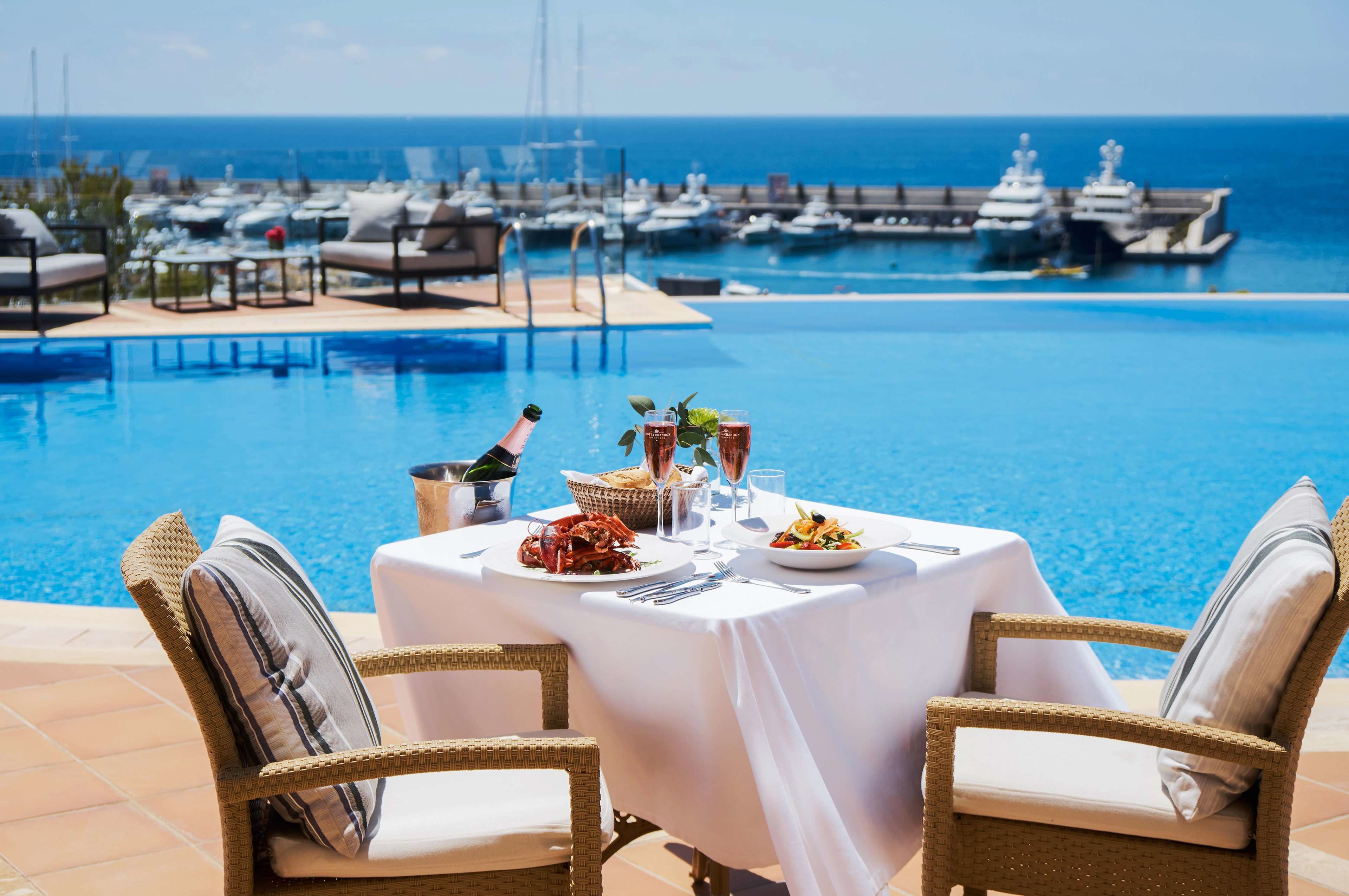 Une table à manger avec vue sur un port de plaisance et l’océan.