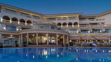 A large hotel with a central pool, multiple balconies, and outdoor seating areas.