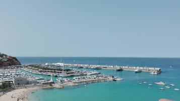 Enjoy waterfront views and stroll along the promenade with access to a sandy beach and a variety of boats docked.