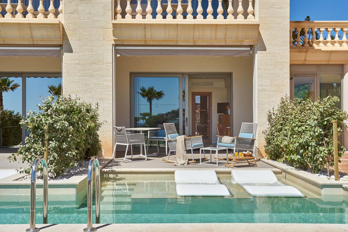 A pool area with lounge chairs, a table, and a door leading to a covered patio.