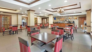 A spacious dining area with multiple tables and chairs, a central chandelier, and a kitchen in the background. - Comfort Inn & Suites Carneys Point - Pennsville (Penns Grove)